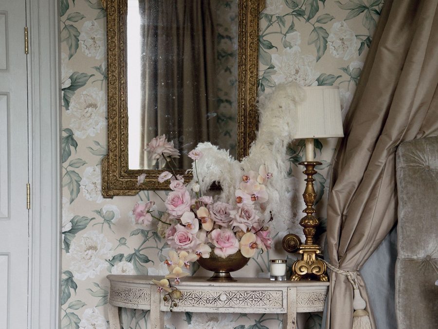 Entry wall in large-scale floral wallpaper with a gilt mirror above a small console table